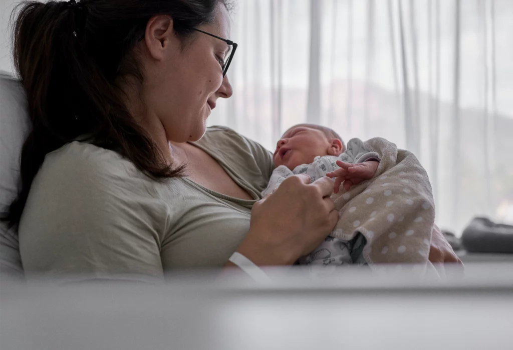 Mutter mit Neugeborenem im Spital während Babyfotoshooting in der Spitalregion Rheintal Werdenberg Sarganserland.